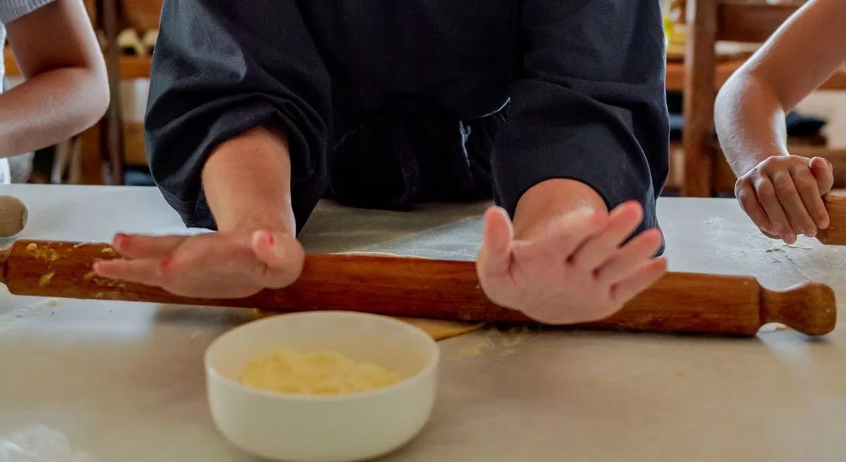 Ospiti che imparano a stendere la pasta a mano durante il corso